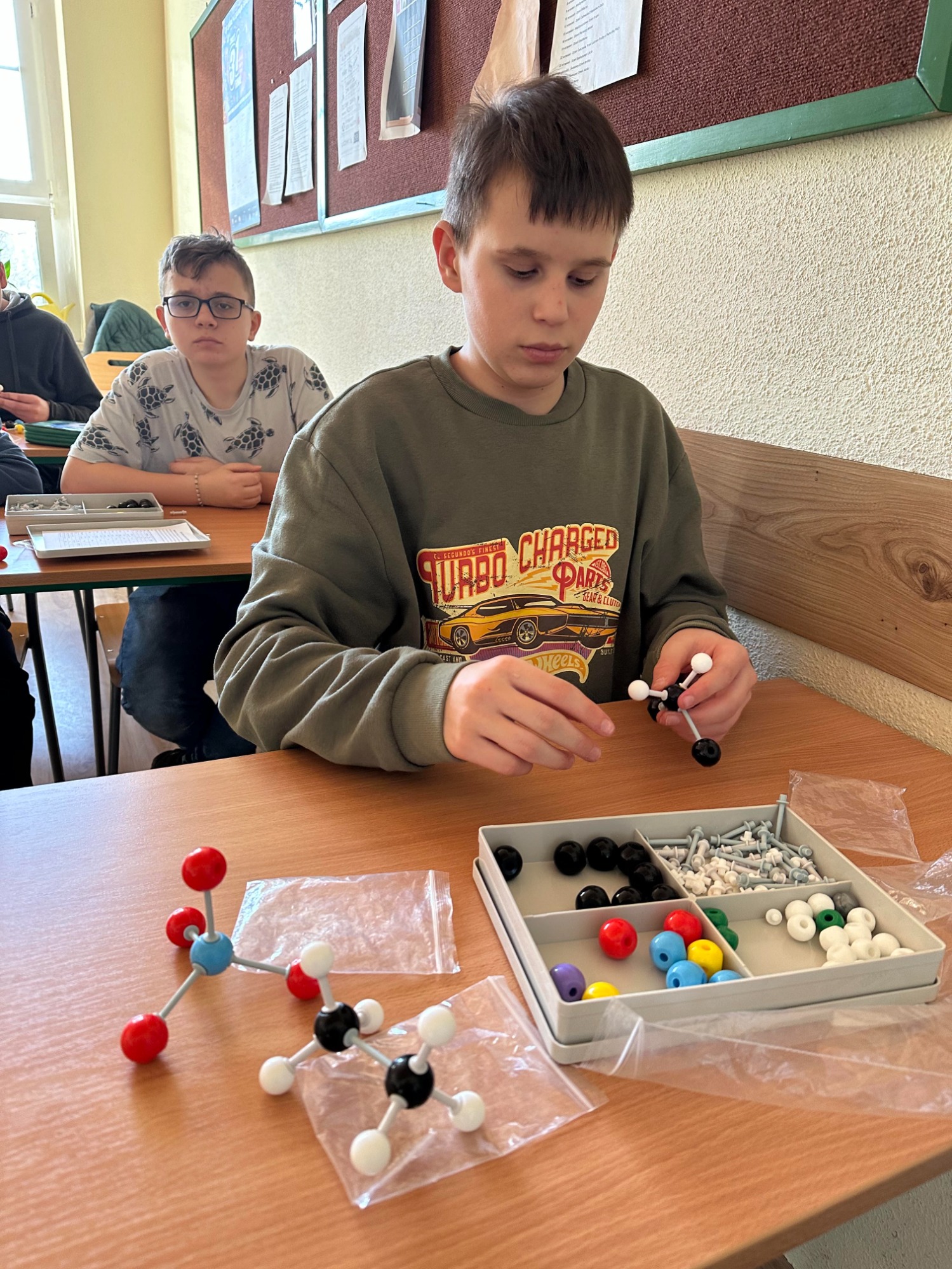 Chłopiec w klasie tworzy kolorowe modele cząsteczki. 