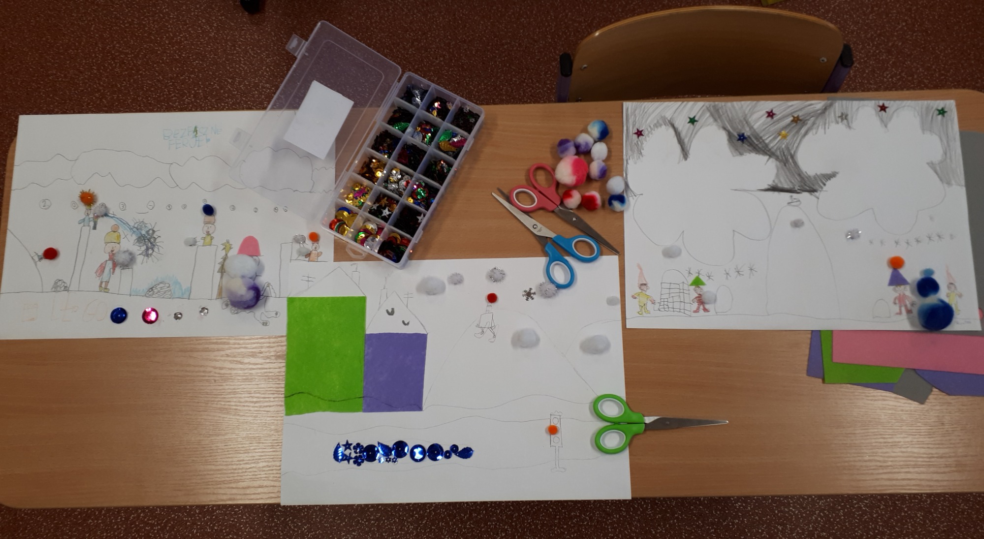 Zdjęcie przedstawia trzy prace plastyczne wykonane na kartce A3, na których uczniowie narysowali siebie podczas zabaw na śniegu oraz wykorzystane do prac materiały.