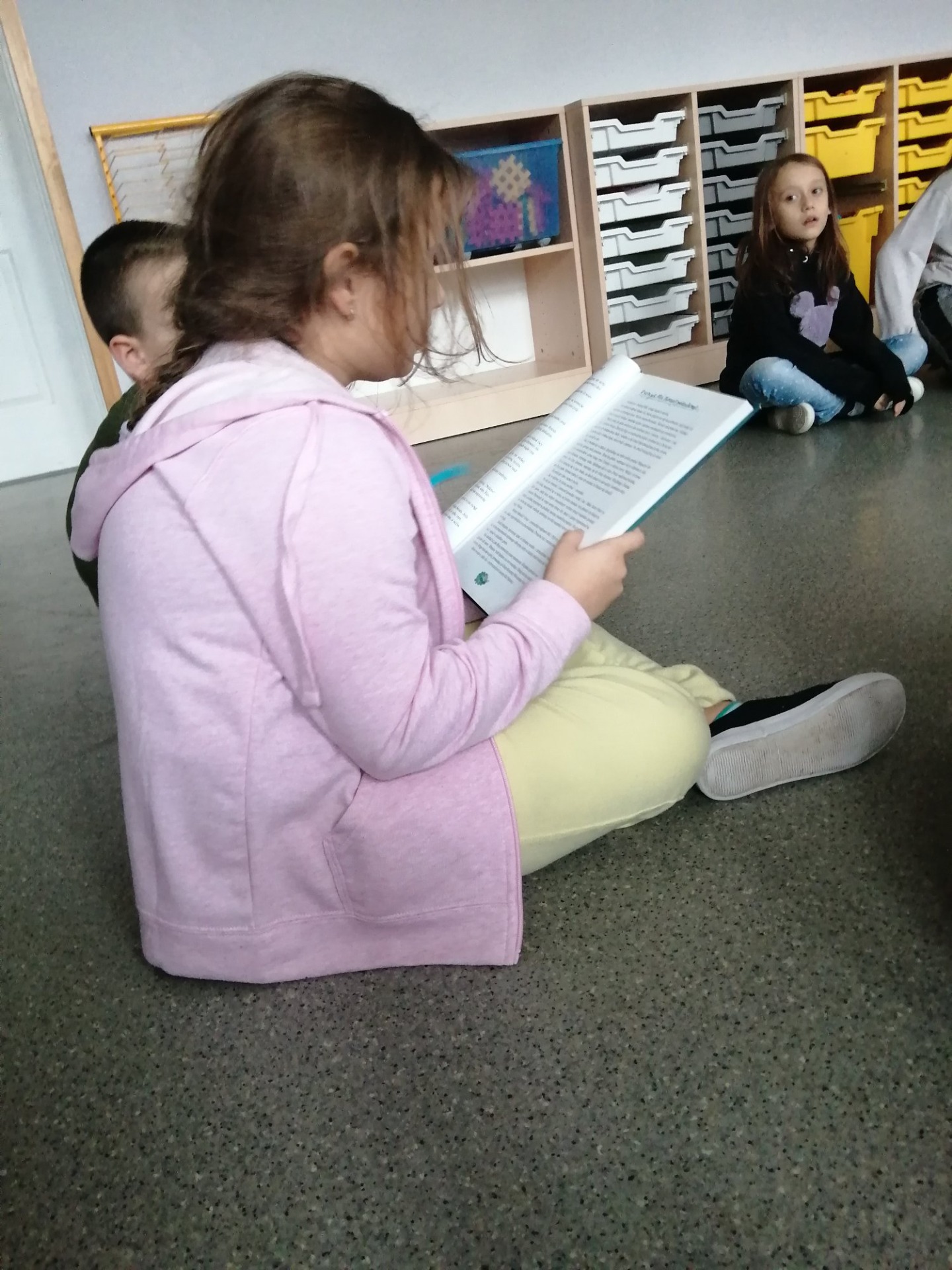 Uczennica podczas czytania młodszym dzieciom