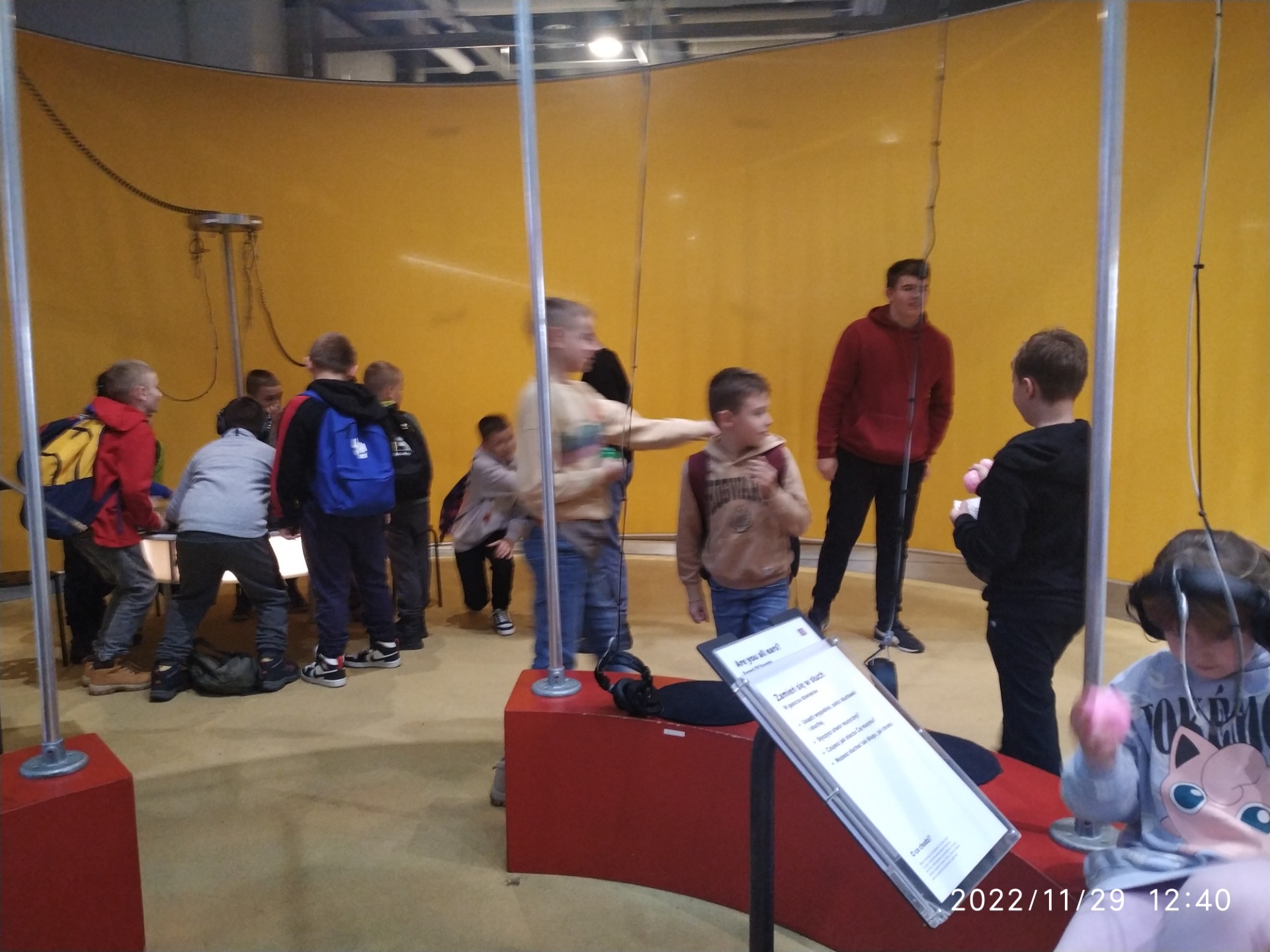 W centrum Nauki Kopernik - grupa uczniów w czasie eksperymentu na żółtym tle. 