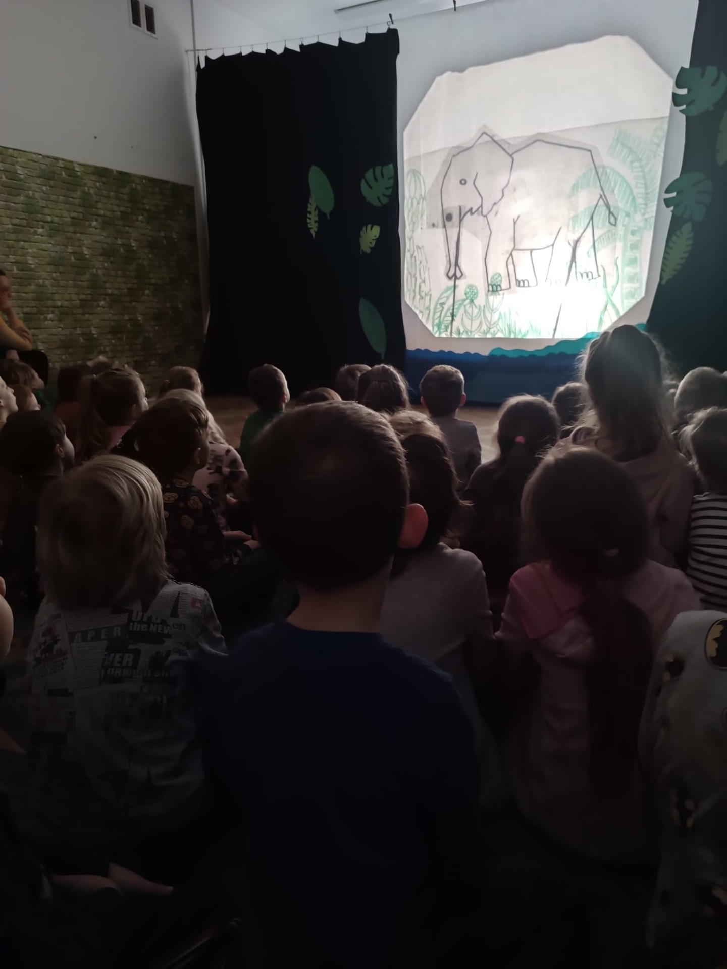 Dzieci z Przedszkola Publicznego Nr 67 "Stokrotka" i Przedszkola Publicznego Nr 23 "Zefirek" oglądają teatr cieni  pt. "Jak mały słonik zawstydził małpy". 