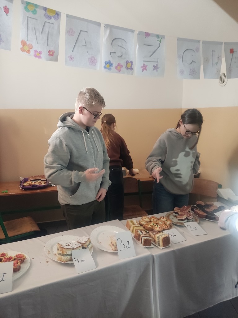 Uczniowie klasy VIII sprzedający ciasta na kiermaszu ciast.