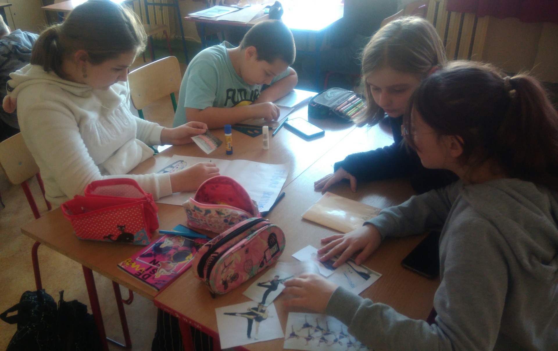 Grupa uczniów klasy 5b, na zajęciach języka angielskiego, pracująca nad projektem o ulubionym sporcie zimowym - łyżwiarstwie figurowym.  
