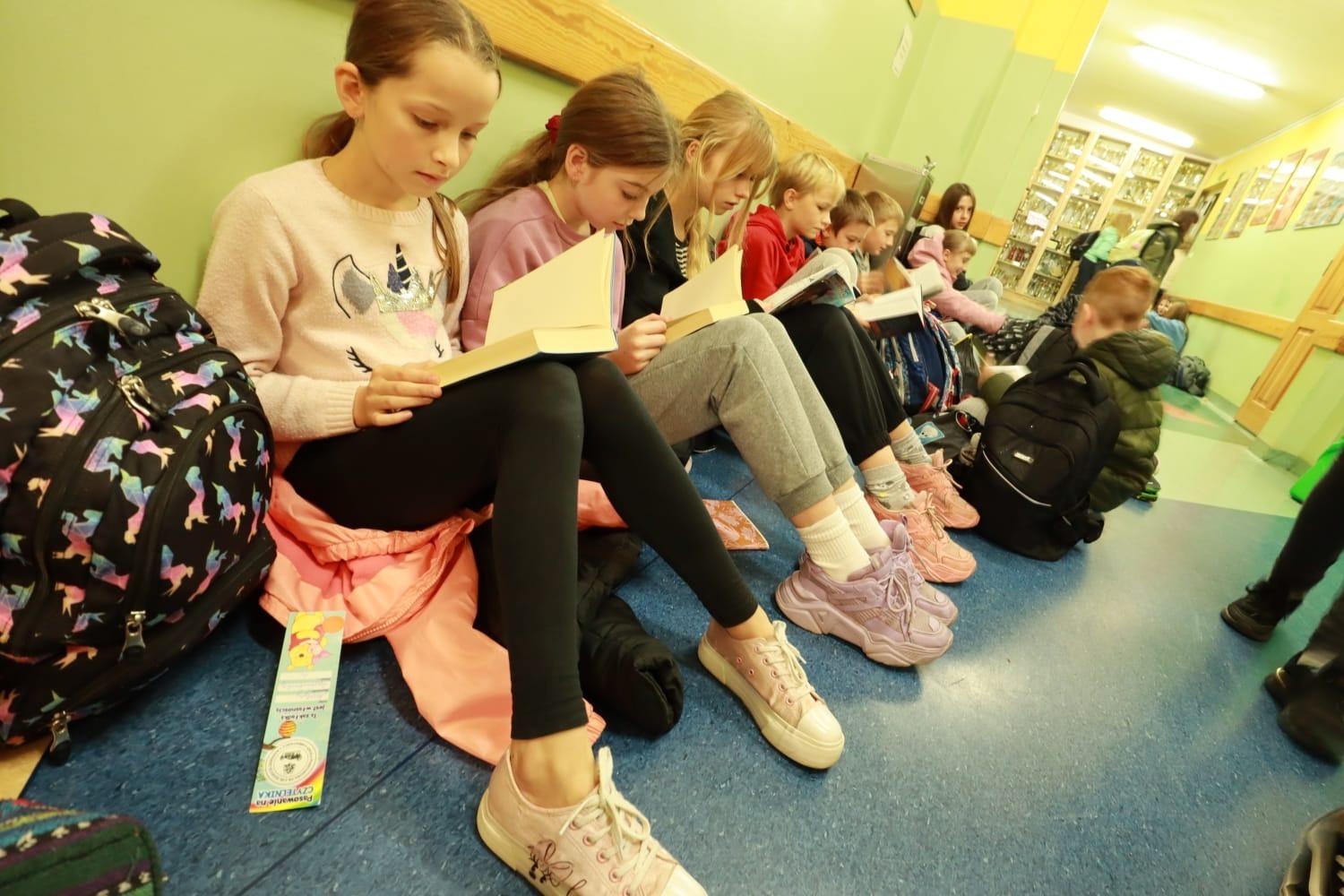 Dzieci siedzą na podłodze  i czytają ksiązki