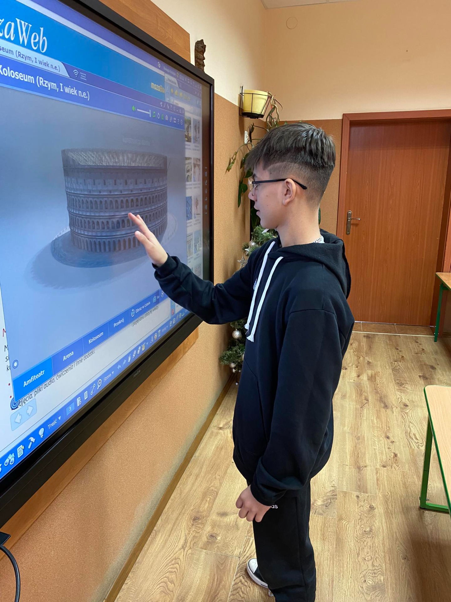 Uczeń stoi przy tablicy interaktywnej i ogląda Koloseum w 3D