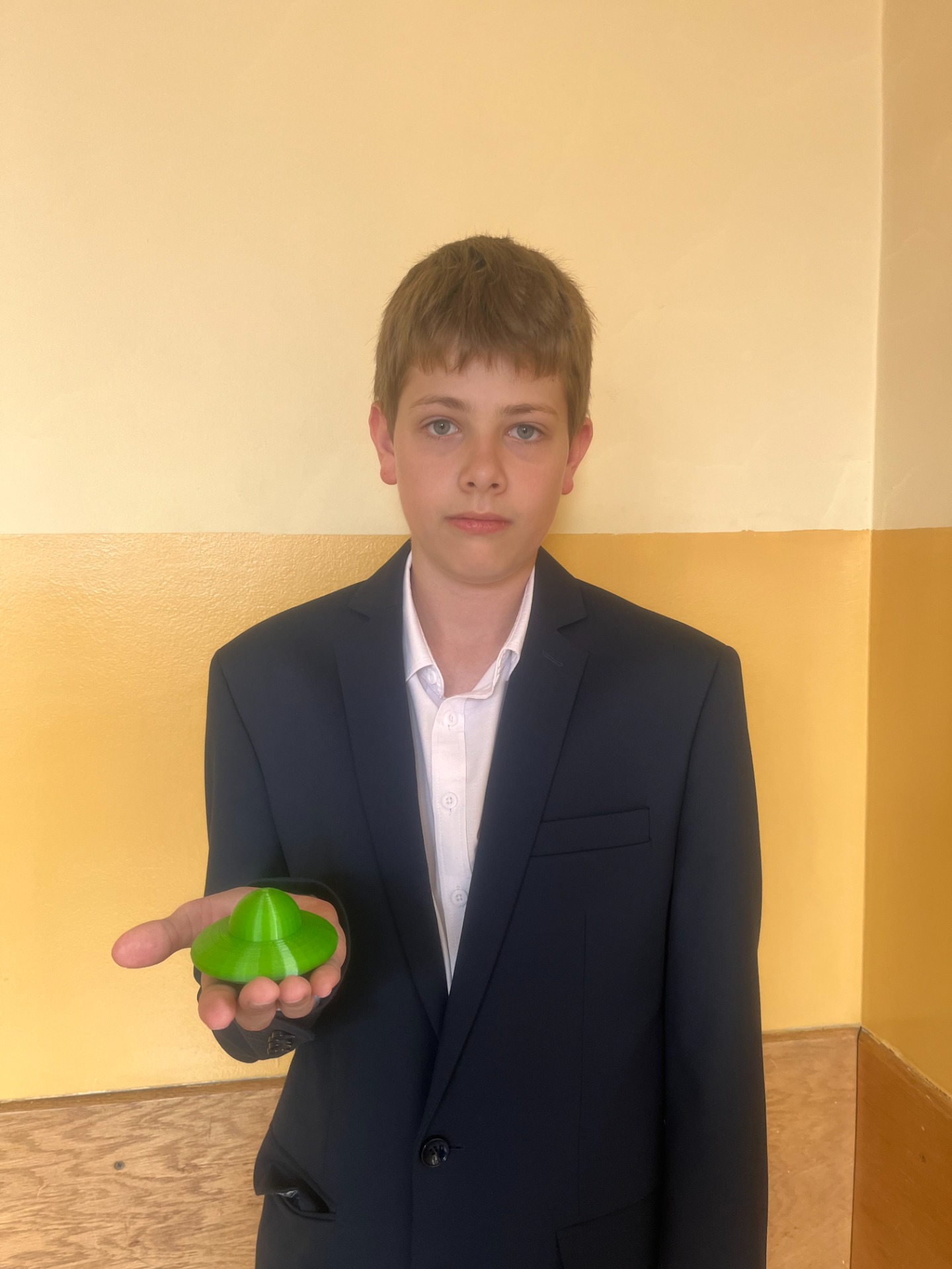 Piotr z klasy 8c wraz z wydrukowanym przez drukarkę 3D modelem własnego projektu.