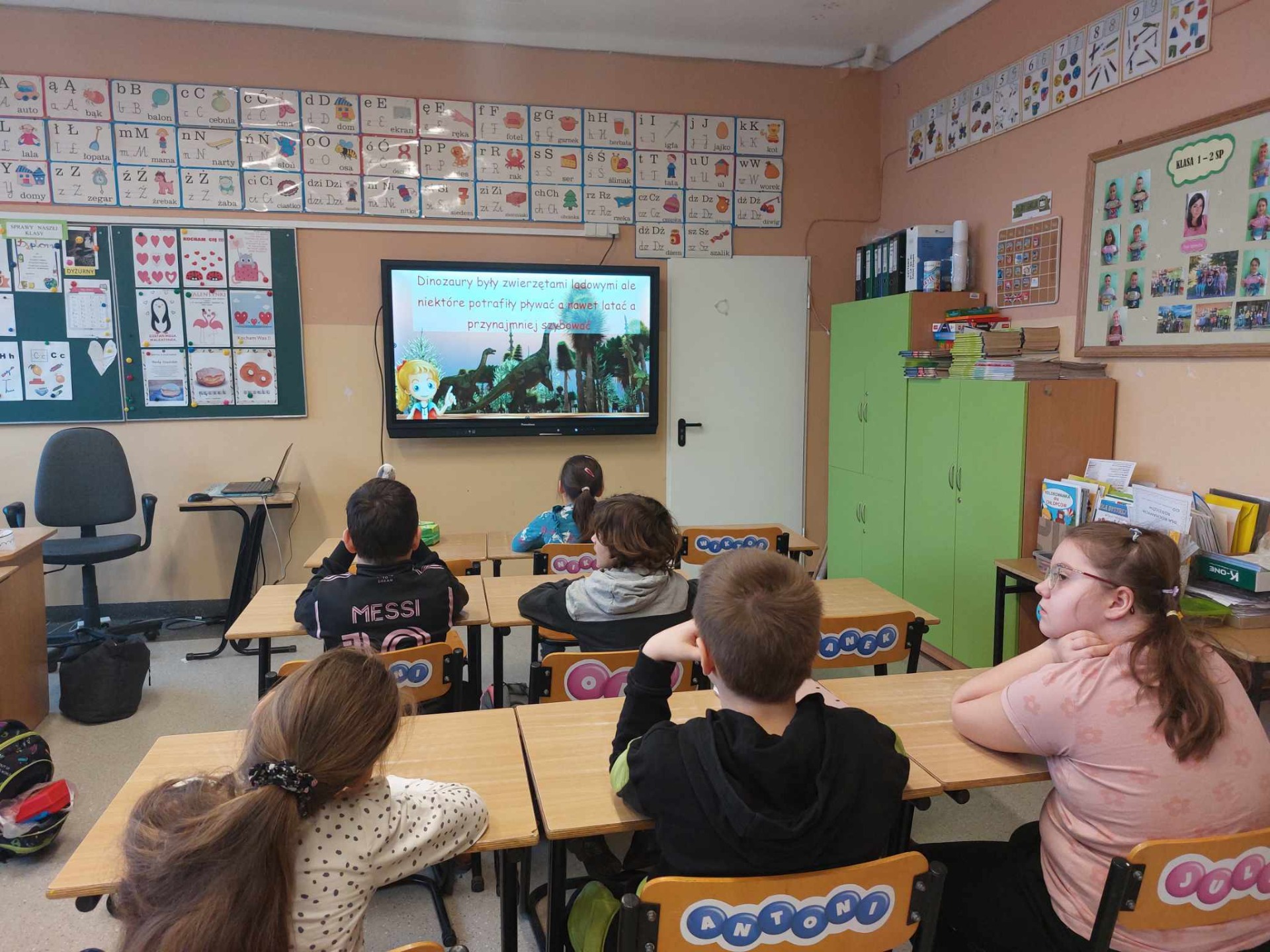 Uczniowie oglądają film o dinozaurach na tablicy interaktywnej